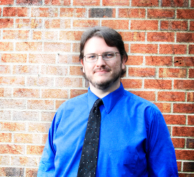 Daniel King in blue shirt and a tie